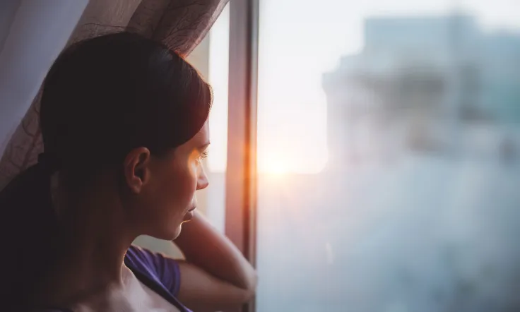 477082000079016003 zc v1 1790314350360 woman gazing out window at sunrise in city 2026 09 23 20 39 00 utc (1)